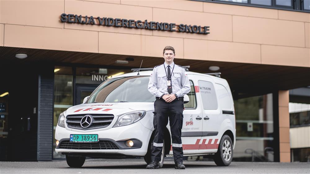 En vekter poserer foran vaktbilen sin foran skolen vår - Klikk for stort bilde